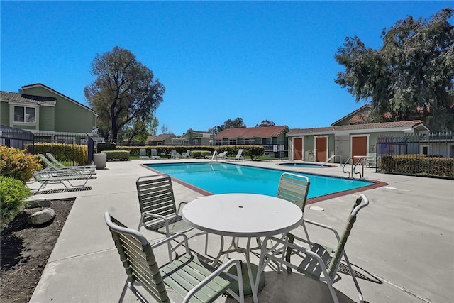 pool featuring a residential view, fence, a community hot tub, and a patio area