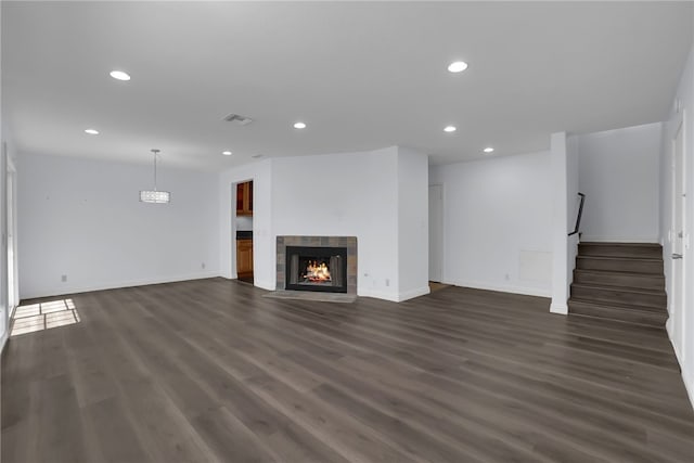 unfurnished living room featuring recessed lighting, stairway, dark wood-style flooring, and a tiled fireplace