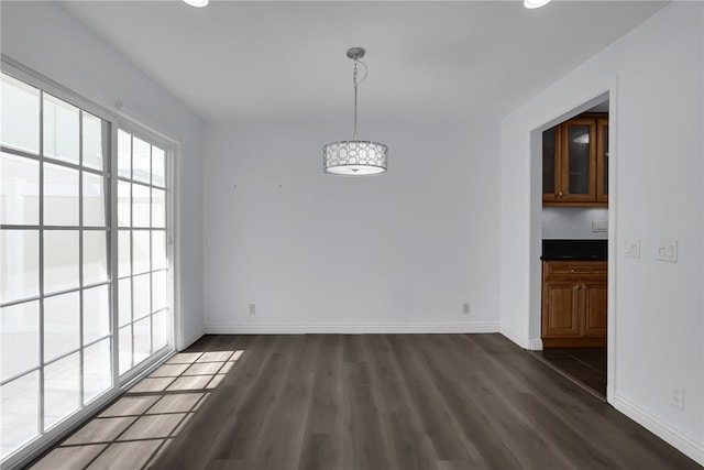 unfurnished dining area with baseboards and dark wood finished floors