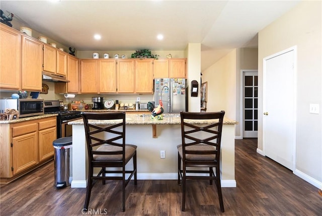 kitchen with baseboards, under cabinet range hood, dark wood finished floors, a center island with sink, and appliances with stainless steel finishes