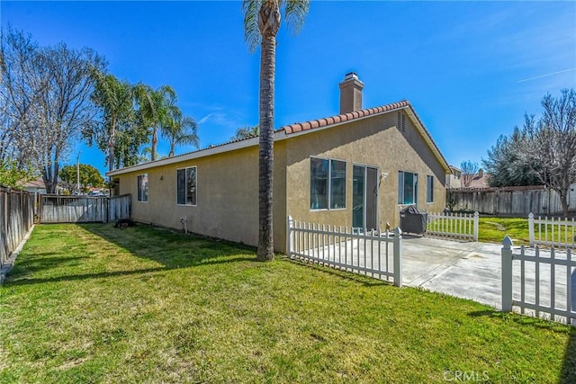 rear view of property with stucco siding, a lawn, a fenced backyard, and a patio area