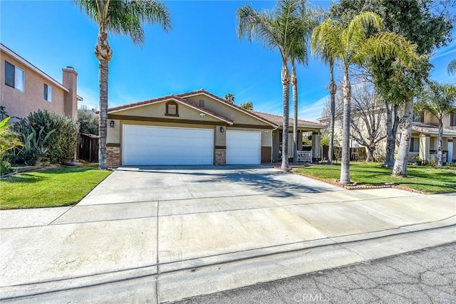 view of front facade with stucco siding, a front lawn, concrete driveway, a garage, and a tiled roof