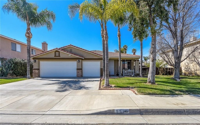 ranch-style home with concrete driveway, a front yard, stucco siding, stone siding, and an attached garage