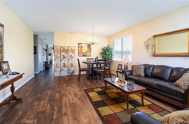 living area with a chandelier, baseboards, and dark wood-style flooring