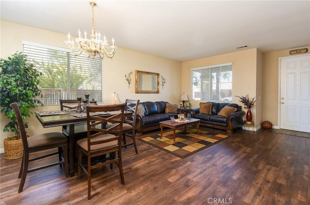 living room with a notable chandelier, visible vents, baseboards, and wood finished floors