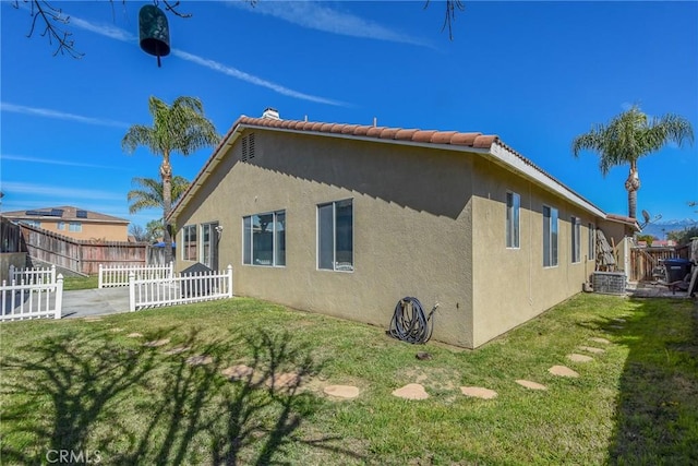 view of side of property featuring a lawn, fence, and stucco siding