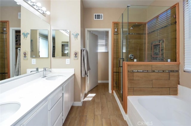 bathroom with visible vents, a stall shower, wood finished floors, a bath, and a sink