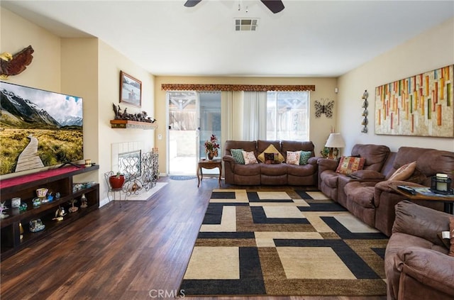 living room featuring visible vents, a ceiling fan, wood finished floors, a fireplace, and baseboards