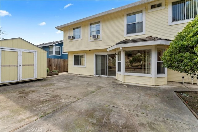 back of property featuring an outbuilding, a patio, cooling unit, fence, and a storage shed