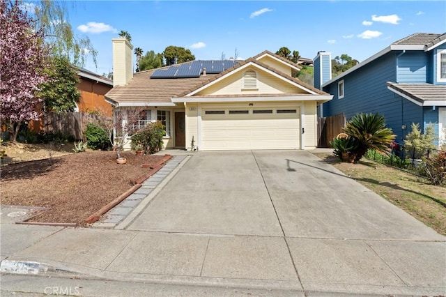 ranch-style house with solar panels, concrete driveway, a garage, and fence