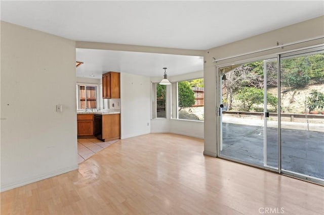 unfurnished living room with a sink, baseboards, and light wood-style flooring