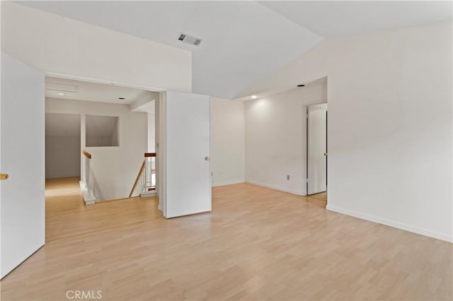 unfurnished room featuring visible vents, baseboards, lofted ceiling, and light wood-style floors