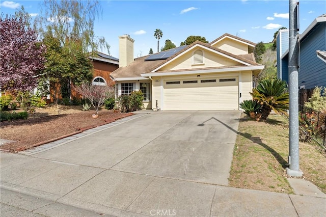 single story home with solar panels, a tile roof, a chimney, a garage, and driveway