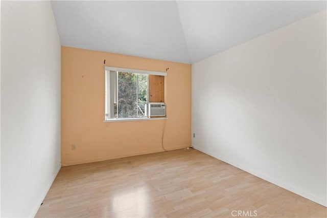 unfurnished room with vaulted ceiling, cooling unit, wood finished floors, and baseboards