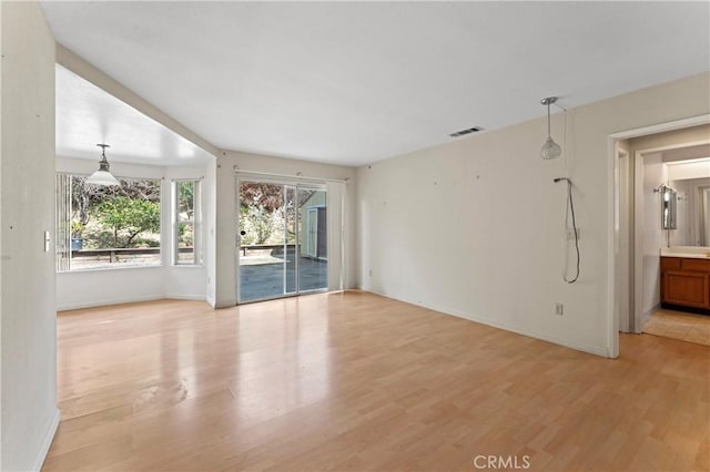 unfurnished room featuring light wood-style floors, visible vents, and baseboards