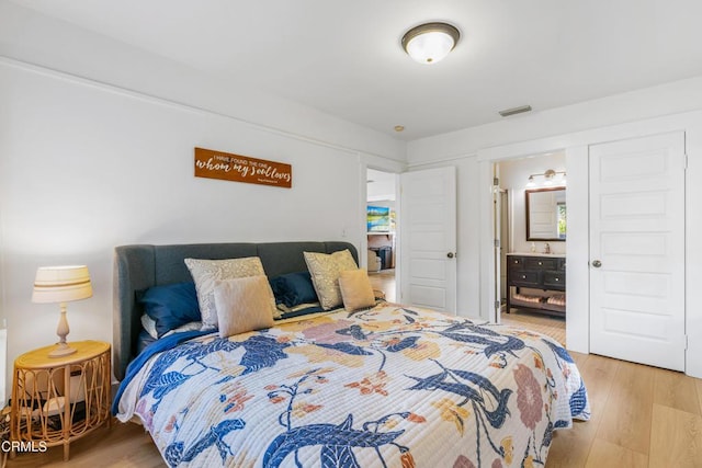 bedroom featuring wood finished floors, visible vents, and ensuite bathroom