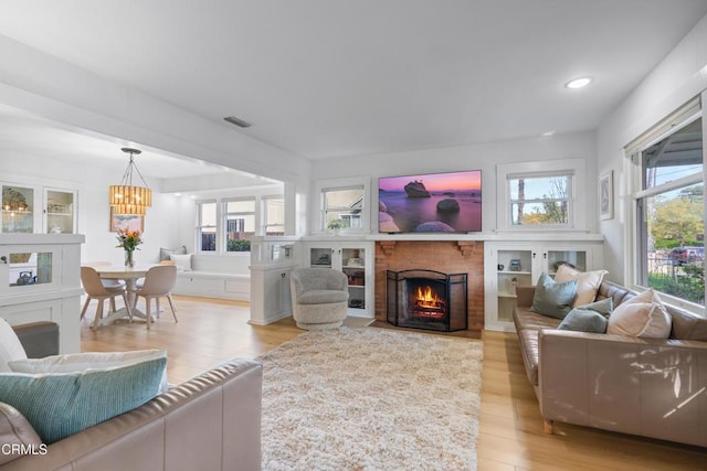 living area featuring a wealth of natural light, visible vents, a fireplace, and light wood-type flooring