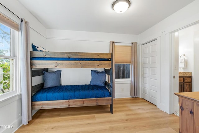 bedroom with light wood-style flooring and ensuite bath