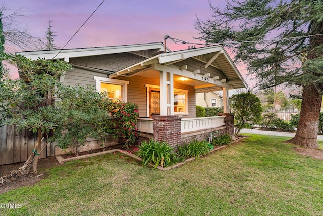 exterior space with covered porch, a lawn, and fence