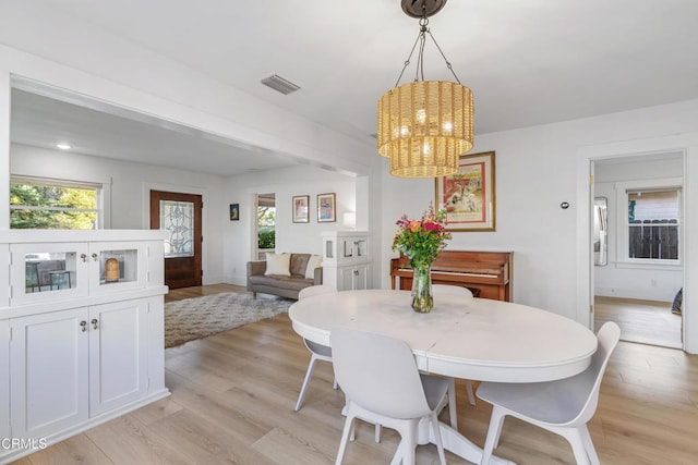 dining space with an inviting chandelier, light wood-style floors, visible vents, and a wealth of natural light