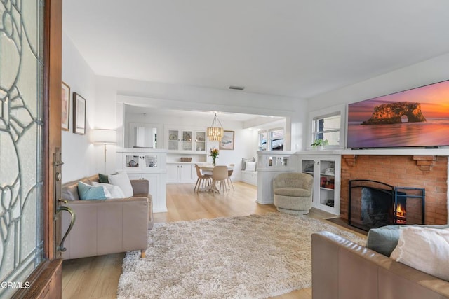 living area with a brick fireplace and light wood-style flooring