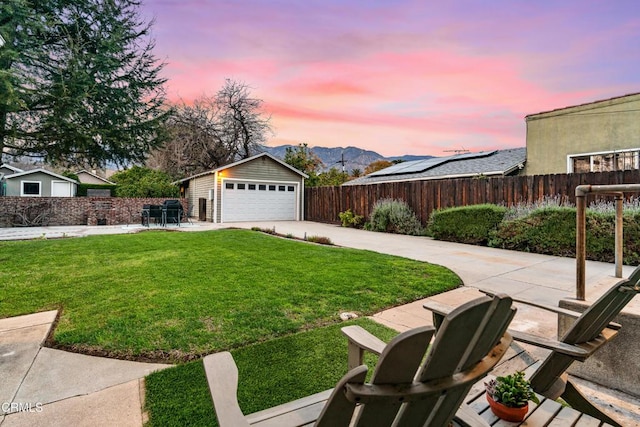 view of yard with an outbuilding, fence private yard, a mountain view, and a detached garage