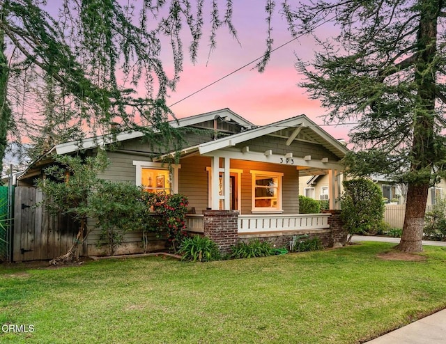 craftsman inspired home with covered porch, a front lawn, and fence