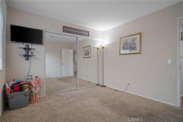 carpeted bedroom with a closet and baseboards