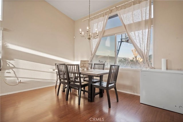 dining room featuring a notable chandelier, baseboards, and wood finished floors