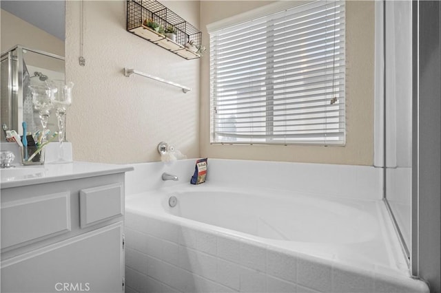 bathroom featuring a wealth of natural light, a shower stall, vanity, and a garden tub