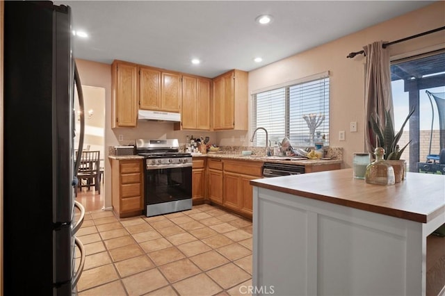 kitchen with under cabinet range hood, light countertops, recessed lighting, stainless steel appliances, and a sink