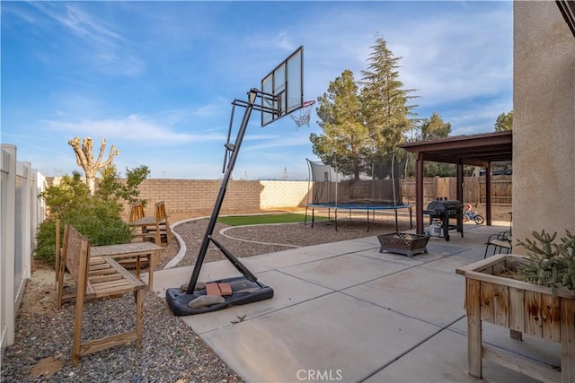 view of patio / terrace with a fenced backyard, grilling area, a fire pit, and a trampoline