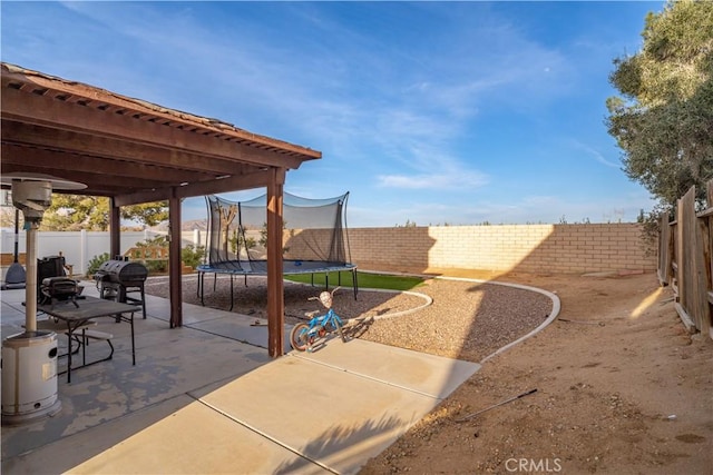 view of patio with a fenced backyard, grilling area, and a trampoline