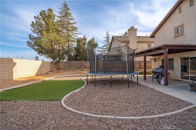 view of yard with a fenced backyard, a patio, and a trampoline