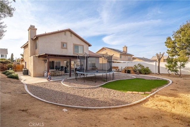 rear view of property with a patio area, stucco siding, a fenced backyard, and a trampoline