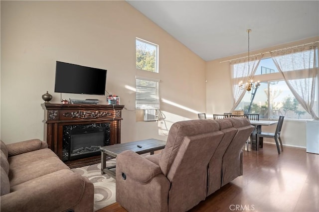 living area featuring high vaulted ceiling, a notable chandelier, wood finished floors, a high end fireplace, and baseboards