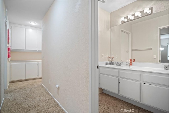 bathroom with double vanity, a textured wall, and a sink