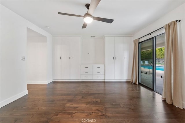 unfurnished bedroom with visible vents, two closets, dark wood-type flooring, baseboards, and access to outside