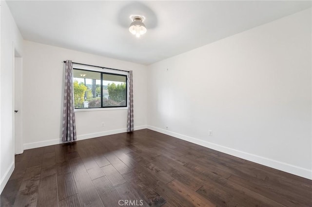 unfurnished room with baseboards and dark wood-style flooring