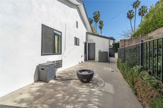 view of patio with central AC unit, a fire pit, and fence