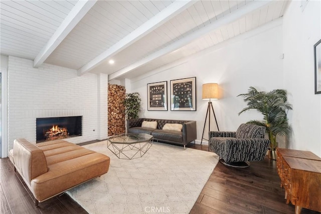 living room featuring lofted ceiling with beams, a brick fireplace, and wood finished floors