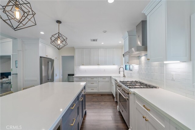 kitchen featuring white cabinetry, wall chimney range hood, high end appliances, and visible vents