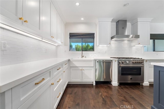 kitchen with a sink, stainless steel appliances, white cabinets, and wall chimney range hood