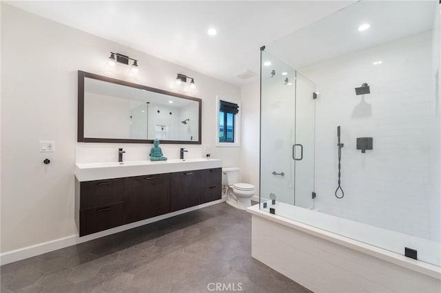 bathroom featuring baseboards, double vanity, a stall shower, a sink, and toilet