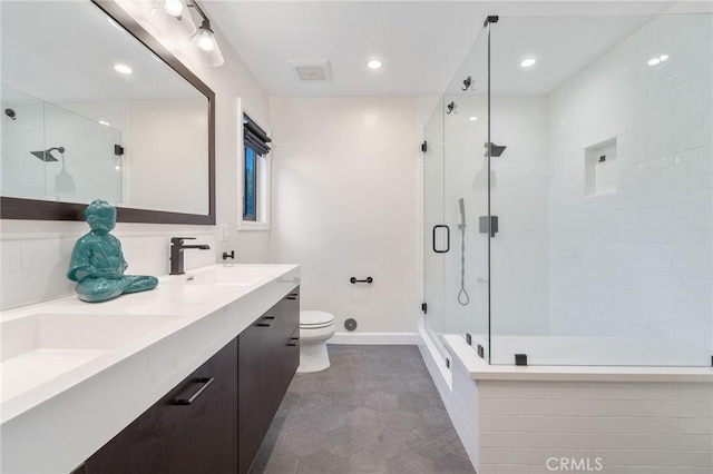 bathroom with a shower stall, toilet, double vanity, and a sink