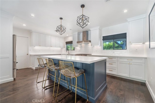 kitchen with dark wood-style floors, white cabinets, light countertops, and wall chimney range hood