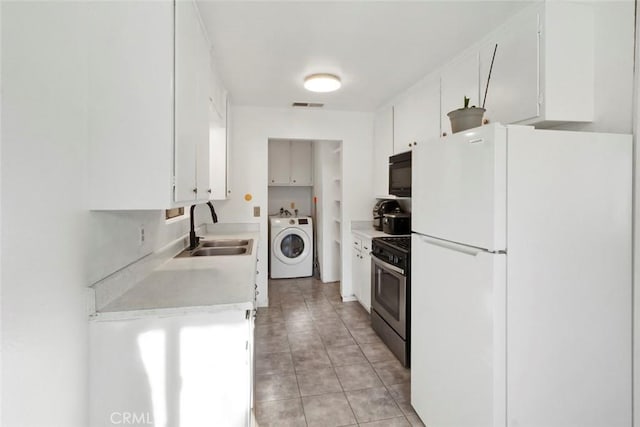 kitchen featuring visible vents, a sink, washer / clothes dryer, freestanding refrigerator, and stainless steel range with gas stovetop