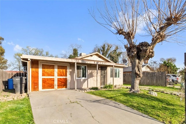 view of front of home featuring a front lawn, concrete driveway, and fence