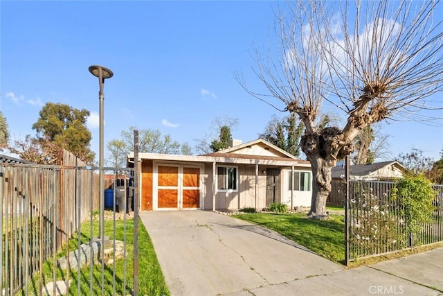 view of front facade featuring concrete driveway, fence private yard, and a front yard