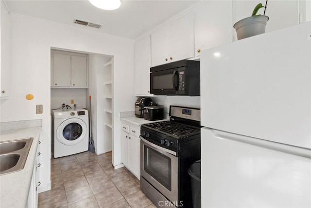 kitchen with visible vents, freestanding refrigerator, gas stove, black microwave, and washer / dryer